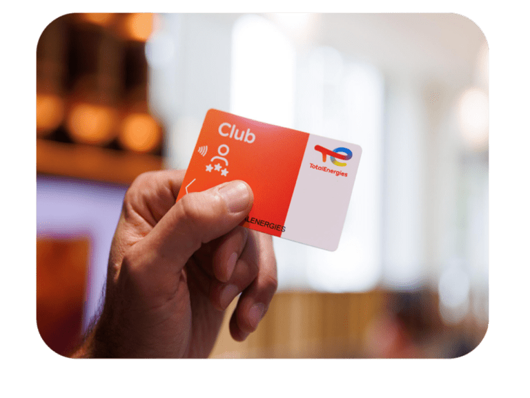 Carte Club TotalEnergies tenue par une personne en station TotalEnergies, utilisée pour les services et paiements en station